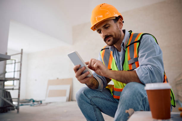 Trabajador en obra consultando plano digital en smartphone durante reforma