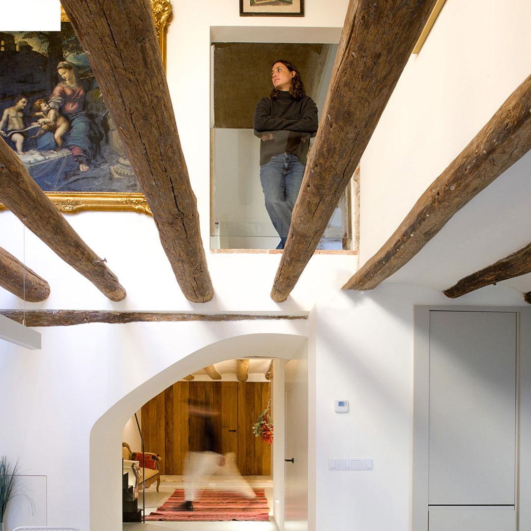 Interior de vivienda rural rehabilitada con vigas de madera vistas y muros encalados
