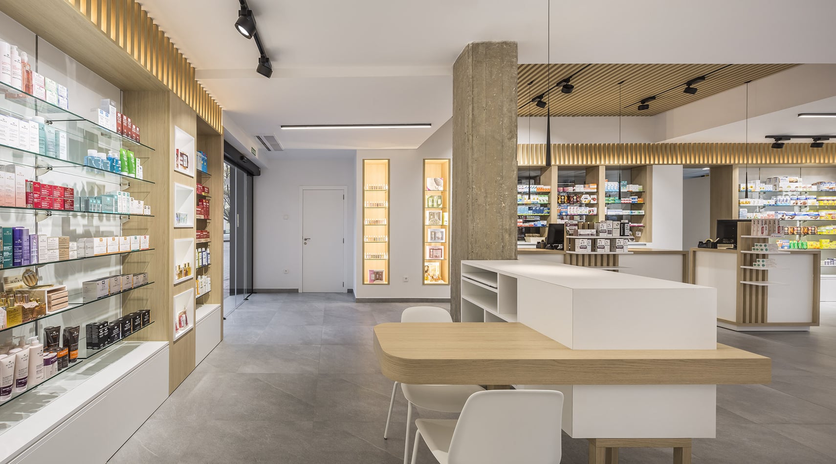 Interior moderno de farmacia reformada con mostrador central e iluminación LED cálida