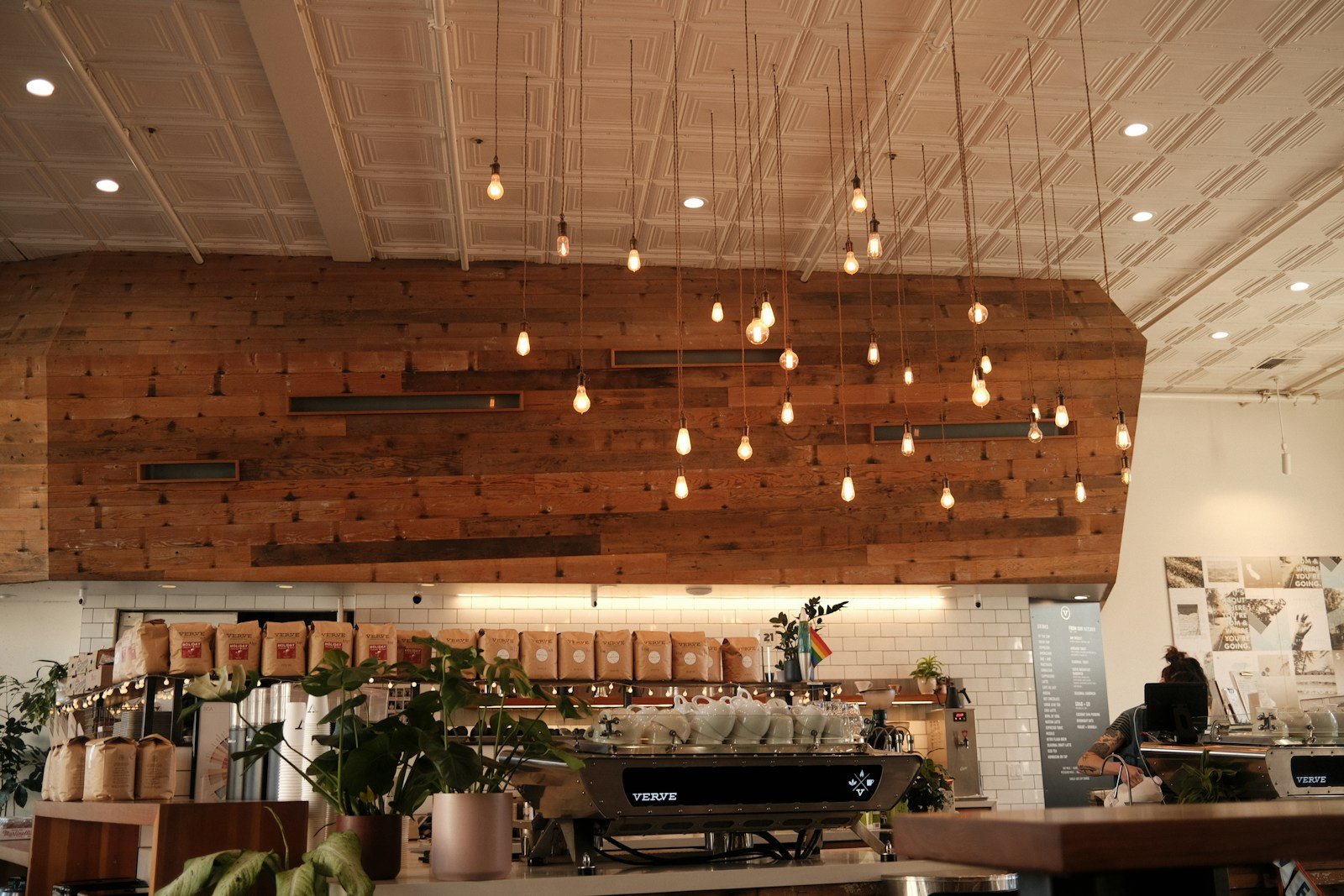 Interior de cafetería con techo acústico de listones y zona de asientos cómoda