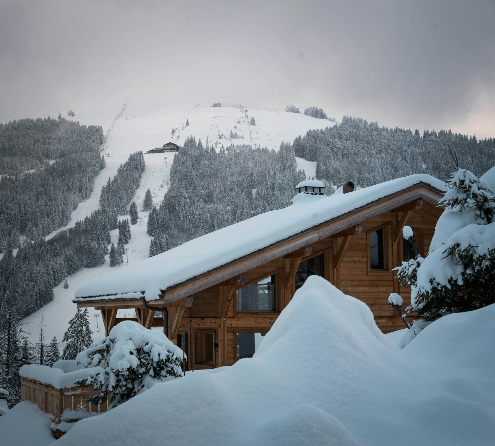 Chalet de piedra en ladera nevada con cubierta inclinada y aleros largos